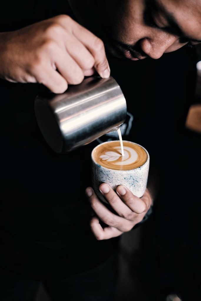 man pouring milk in coffee